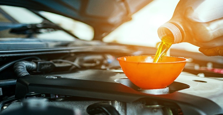Pouring engine oil into a car engine.