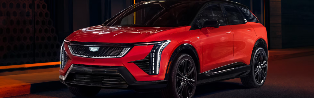 Red Cadillac OPTIQ electric SUV parked on a city street at night